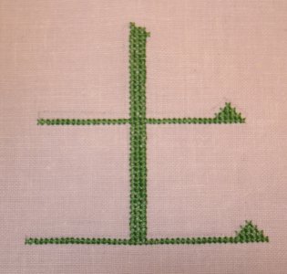 Kreuzstich-Beispiel: Das Kanji für Erde in grünem Kreuzstich auf feinerem Leinengrund, Vorlage in Pinselschrift.